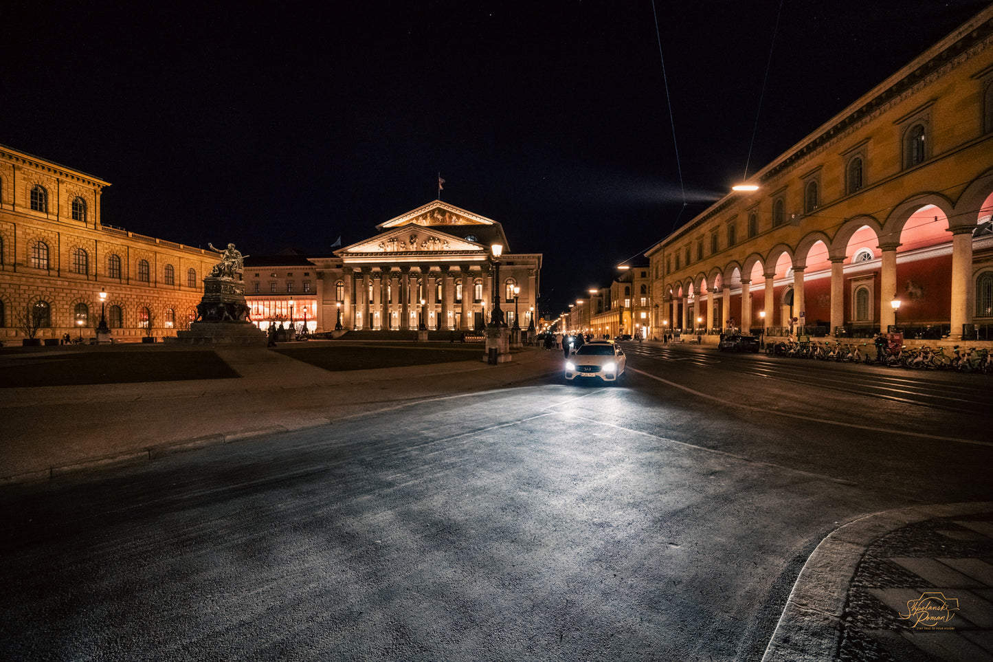 Nationaltheater Munich illuminated at night with a car on the empty square