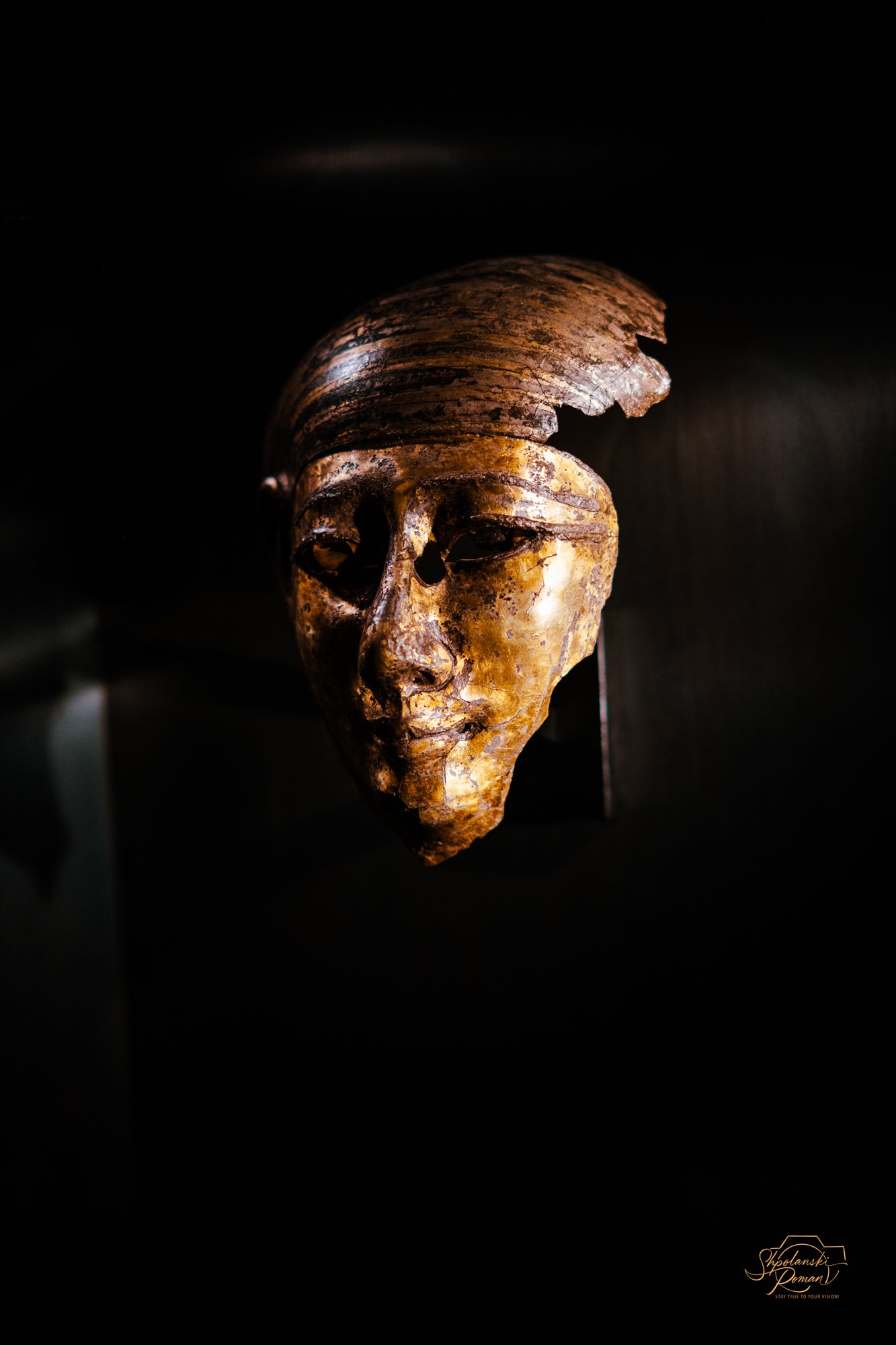 Golden Egyptian funerary mask lit in the dark