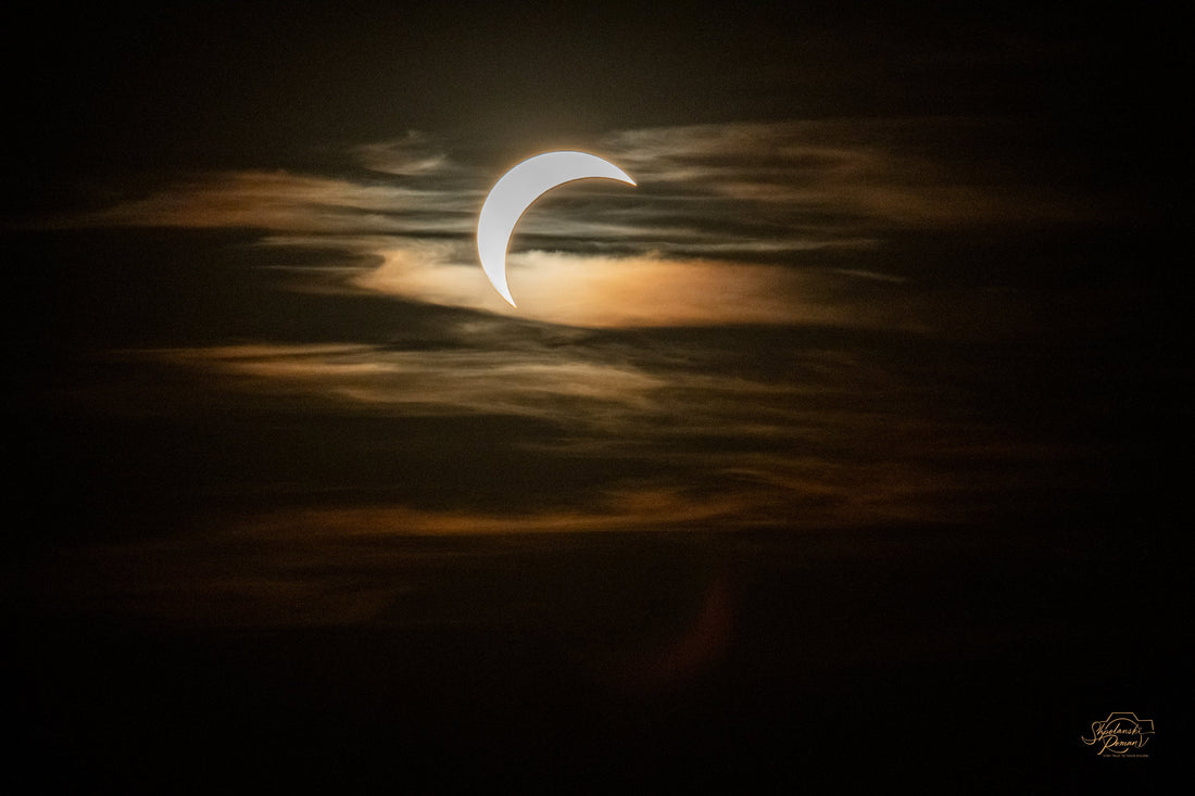Crescent of the partially eclipsed sun glowing through golden clouds over Munich, 12 August 2026