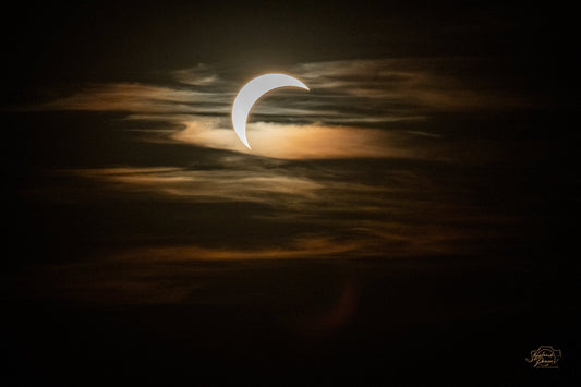 Crescent of the partially eclipsed sun glowing through golden clouds over Munich, 12 August 2026