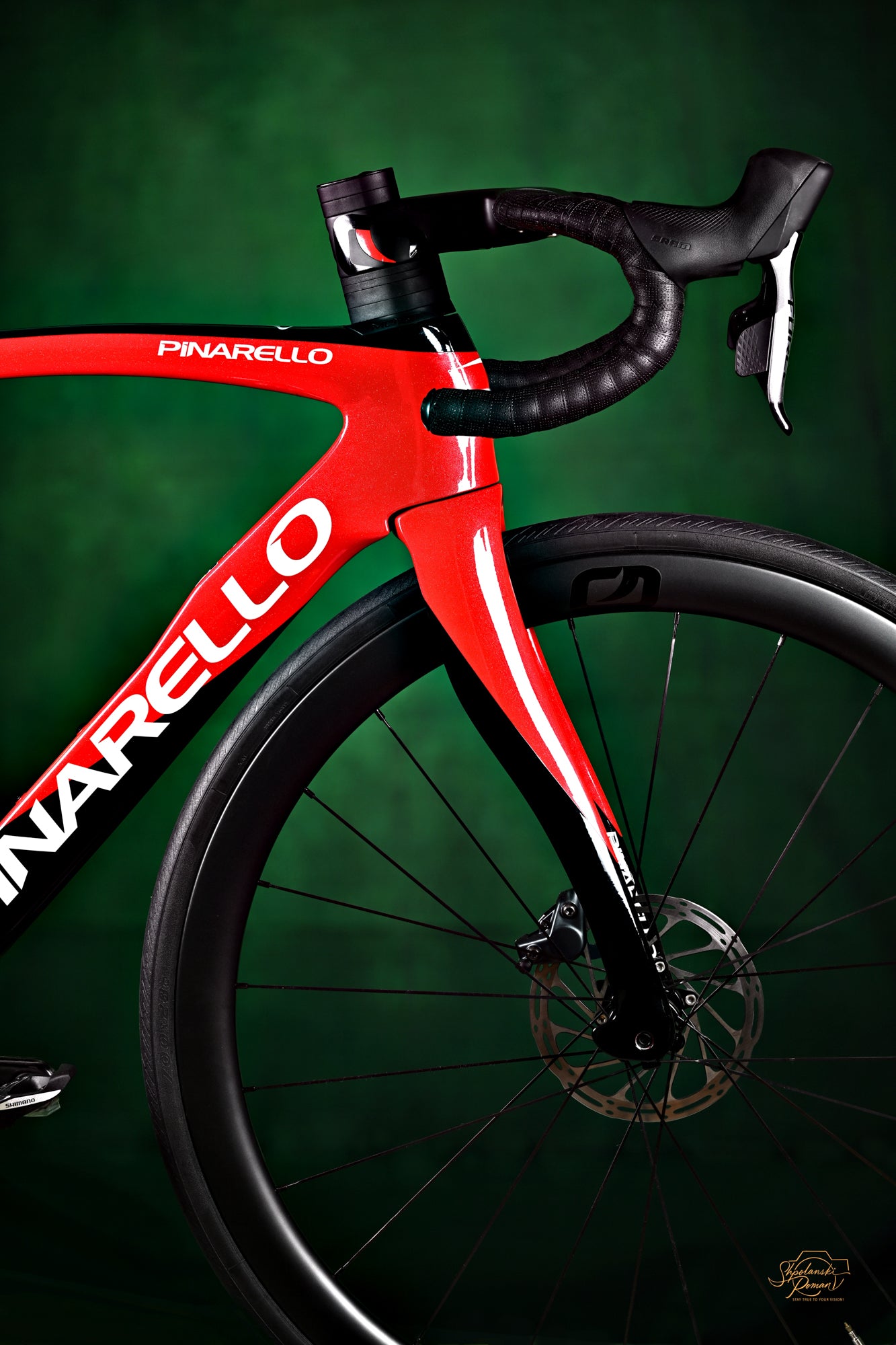 A red Pinarello racing bike against a green background