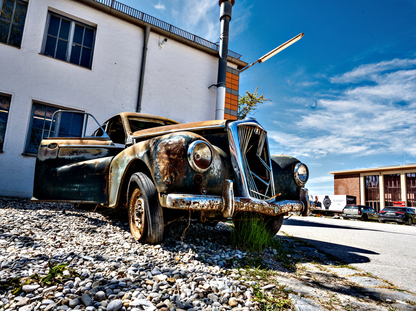 A rusted vintage car under a bright sky