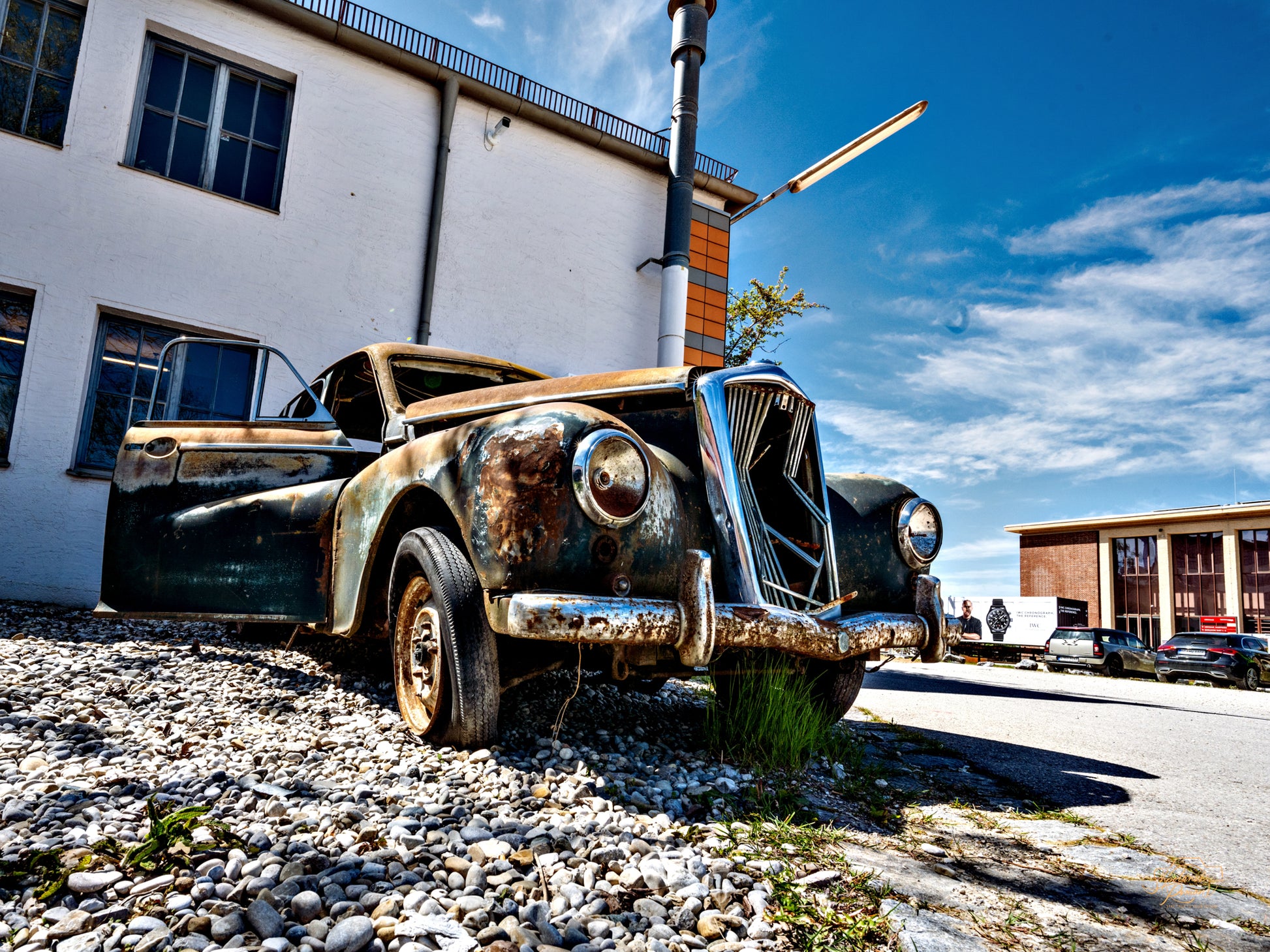 A rusted vintage car under a bright sky