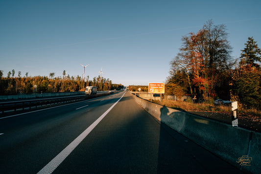 An open road lined with autumn trees at sunset