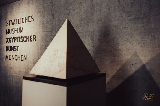 Alabaster pyramid before a concrete wall with the museum name in German