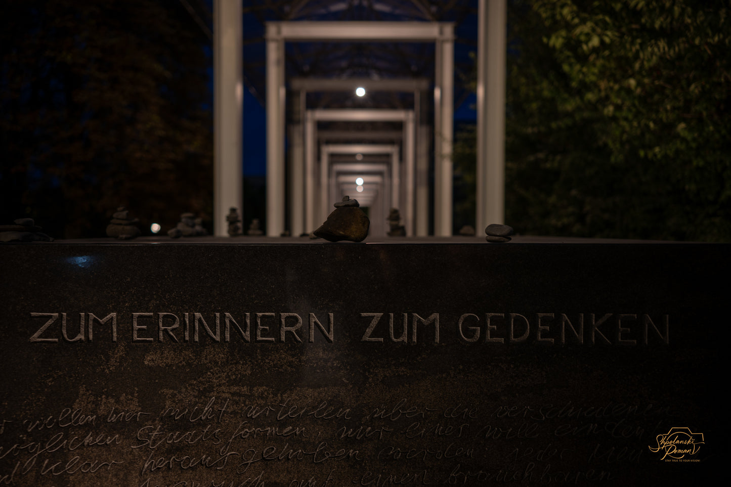 A dark corridor of doorways with faint memorial text