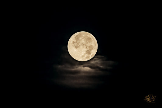A full moon breaking through clouds at night